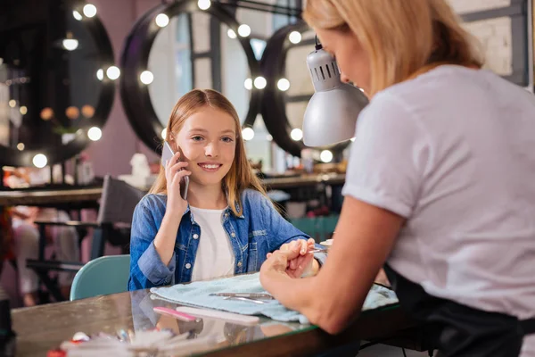 Mooi meisje praten over de telefoon terwijl het hebben van nagels gedaan — Stockfoto