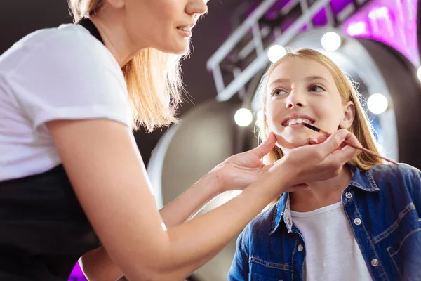 Kızlar dudaklarına ruj uygulamak için fırça kullanarak makyaj sanatçısı