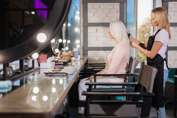 Side view of senior lady having her hair straightened — Stock Photo, Image