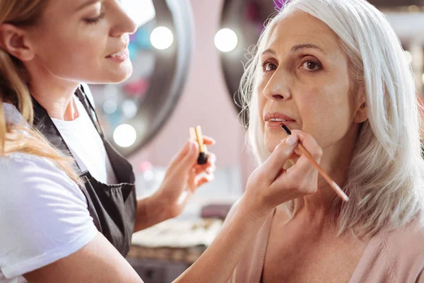 Okouzlující umělec makeupu dokončovali Zenske make-up s rtěnkou — Stock fotografie