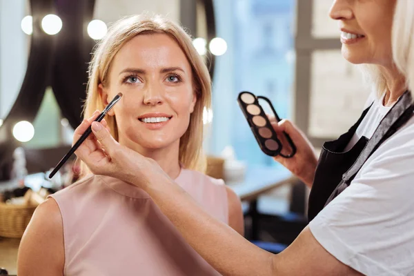 Zblízka mladé ženy dostat její oční make-up provádí — Stock fotografie