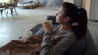 Hasta genç kadın çayla ısınıyor.