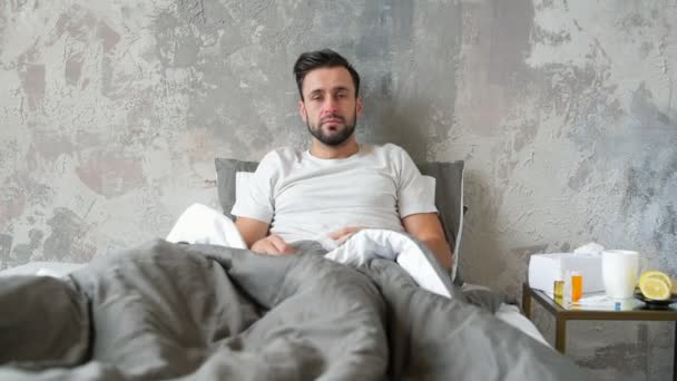 Zieke man in bed zijn rode neus blazen — Stockvideo