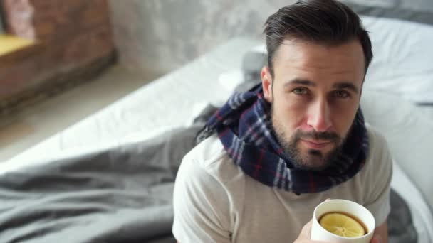 Caballero enfermo arreglando bufanda mientras bebe té — Vídeos de Stock