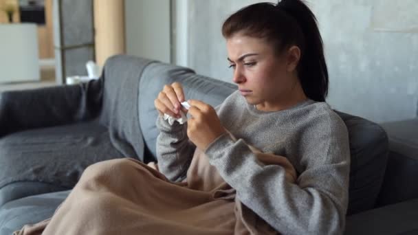 Tired millennial girl having high temperature sitting on sofa — Stock Video