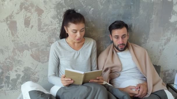 Young lady reading her ill husband book — Stock Video