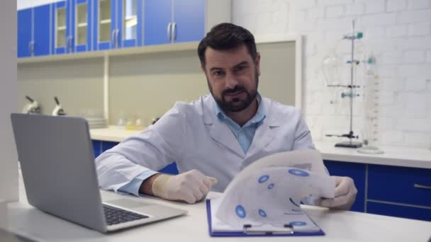 Příjemný vypadající vědec úsměv do kamery při práci — Stock video