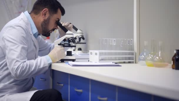 Pesquisador masculino examinando espécime e fazendo anotações — Vídeo de Stock