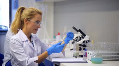 Neşeli kadın test tüpleri bitkilerde tahıl incelenirken gülümseyen