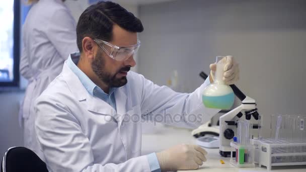 Зрілий дослідник проводить експеримент в лабораторії — стокове відео