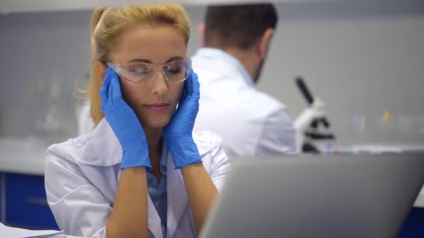 Müde Frau massiert Schläfen, während sie Kopfschmerzen im Labor hat