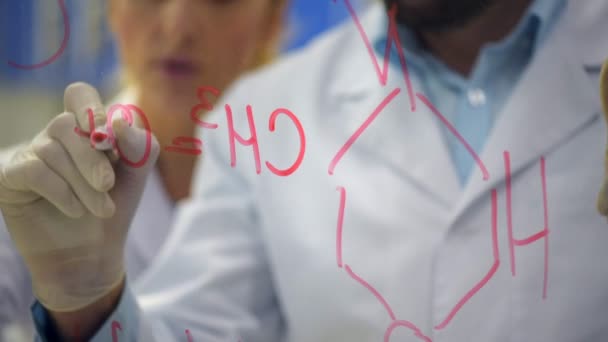 Nahaufnahme eines männlichen Forschers, der chemische Formel auf Glas zeichnet — Stockvideo