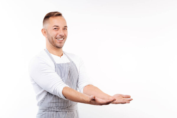 Smiling man in apron stretching out his hands