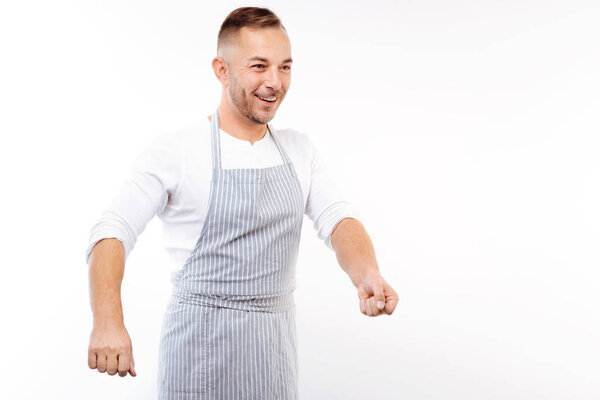 Cheerful man in apron imitating the process of frying