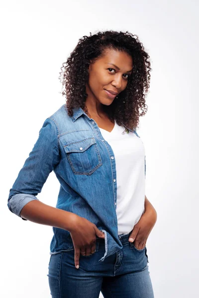 Curly woman posing while holding hands in pockets — Stock Photo, Image