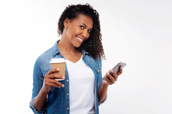 Mujer bonita sonriendo mientras lee el mensaje y sostiene el café —  Fotos de Stock