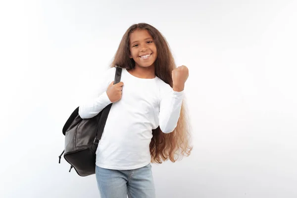 Upbeat schoolgirl with backpack raising hand in celebration — Stock Photo, Image