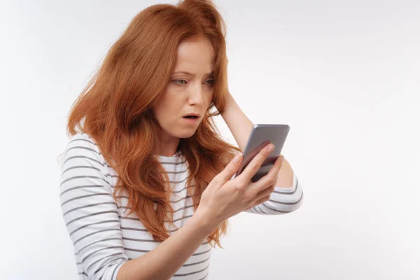 Rudowłosa kobieta będąc w szoku po przeczytaniu wiadomości — Zdjęcie stockowe