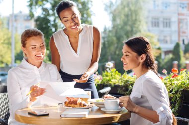 Üç kadın öğle yemeği sırasında araştırma sonuçlarını tartışıyor