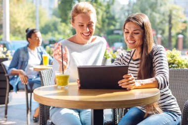 Tablet kafede video izlerken iki neşeli kadın
