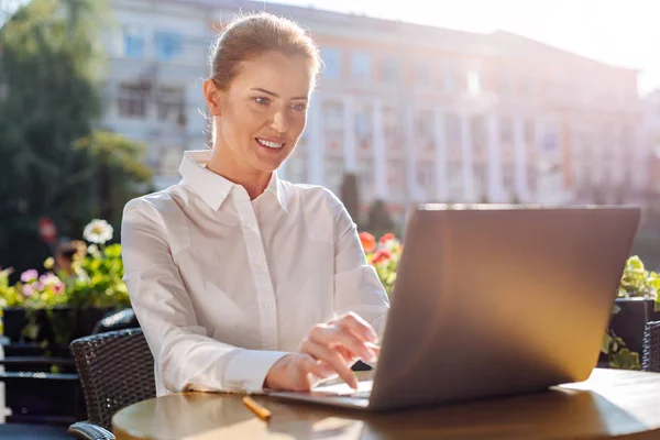 Charmiga unga kvinna som arbetar på laptop i café — Stockfoto