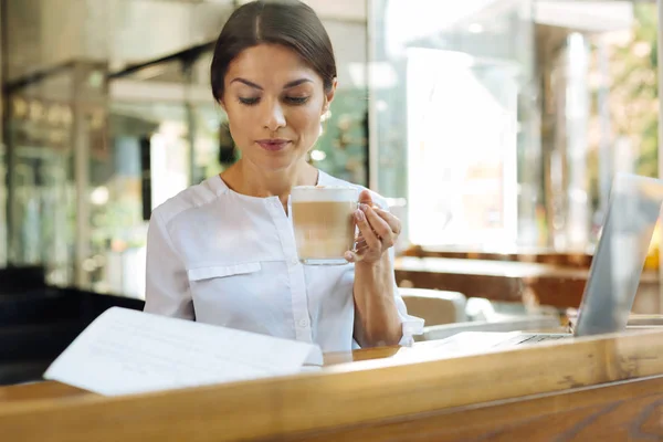 Mujer joven leyendo contrato mientras bebe café con leche —  Fotos de Stock