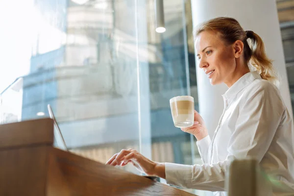 Inspirován žena pití latte a prohlížení webu v kavárně — Stock fotografie