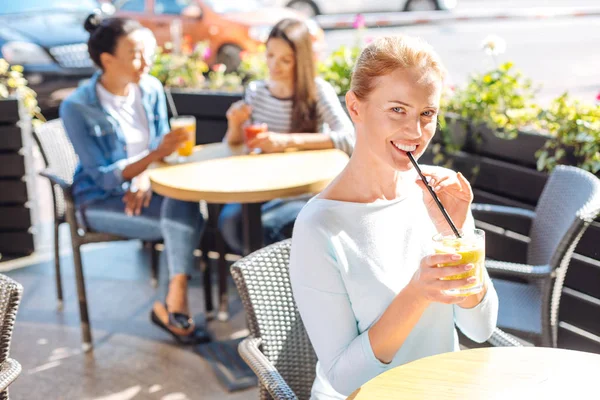 Charmig kvinna poserar medan dricka smoothie i café — Stockfoto