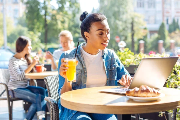 Glad kvinna som håller ett glas juice medan du chattar — Stockfoto