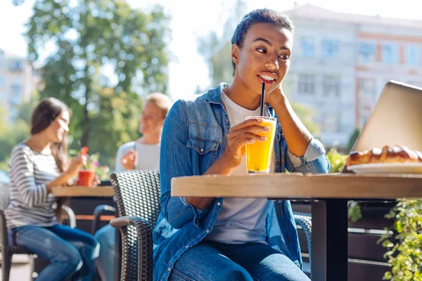 Gladlynt kvinna dricker juice medan du tittar på Tv-show i café — Stockfoto