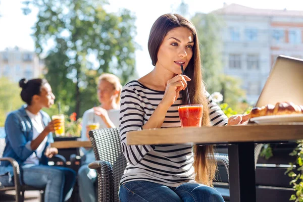 Dizüstü bilgisayar kullanırken sipping güler yüzlü genç kadın