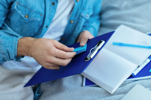 Close up of male hand sticking note on clipboard — Stock Photo, Image