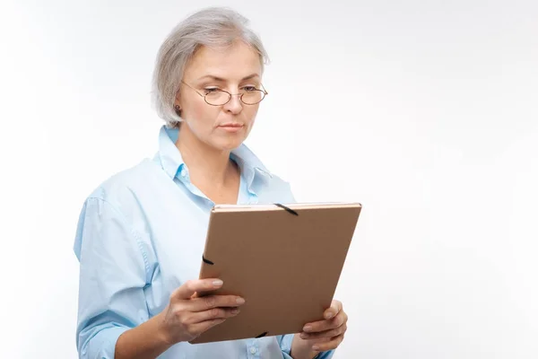 严重灰色头发的女人，从文件夹中读取文件 — 图库照片