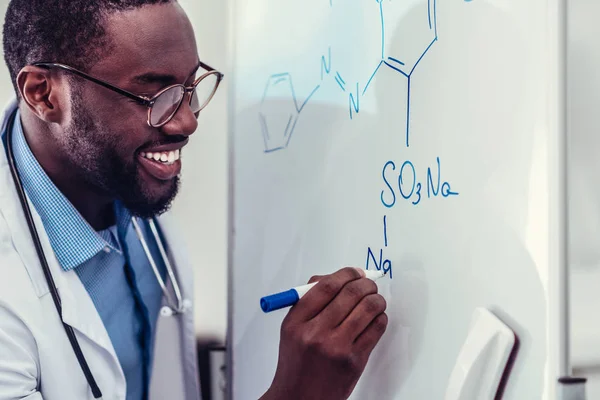 Ενθουσιασμένος αφρικανικό αμερικανικό ιατρικό εργαζόμενο σχεδίασης χημικής σχεδίασης — Φωτογραφία Αρχείου