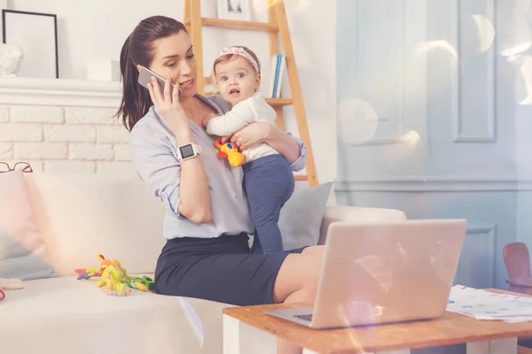 Zajęty pracownikowi siedzi w domu z jej dziecko — Zdjęcie stockowe