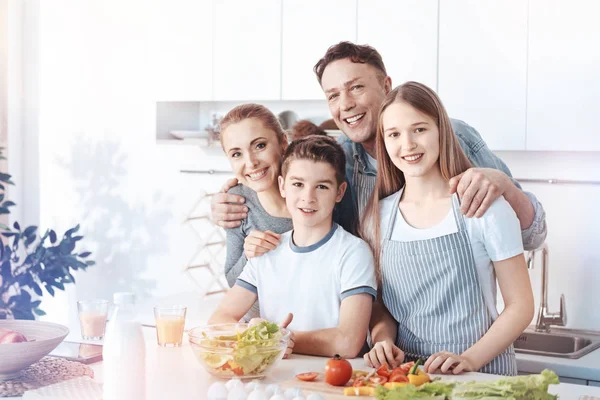 Сяюча сім'я позує на камеру під час приготування їжі — стокове фото