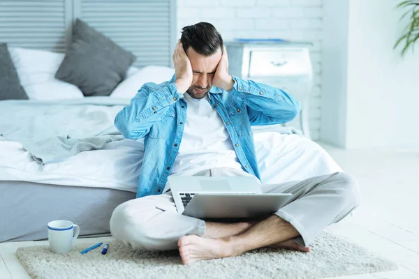 Agotado hombre autónomo presionando la cabeza mientras trabaja — Foto de Stock