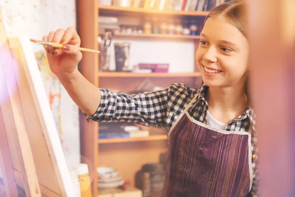 Chica encantadora sonriendo mientras dibuja con pinturas al óleo — Foto de Stock