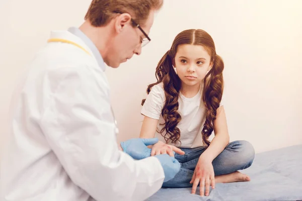 Upset kid crossing legs while being in consulting room — Stock Photo, Image
