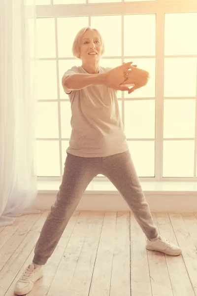 Comprimento total da mulher idosa encantada fazendo exercícios matinais — Fotografia de Stock