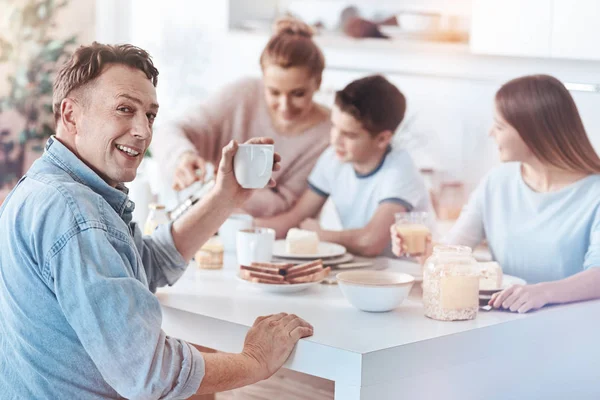 Vänliga far poserar för kameran medan man äter med familj — Stockfoto