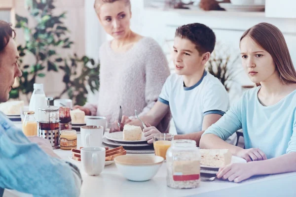 Verbaasd tienermeisje op zoek naar de vacature tijdens het ontbijt met familie — Stockfoto