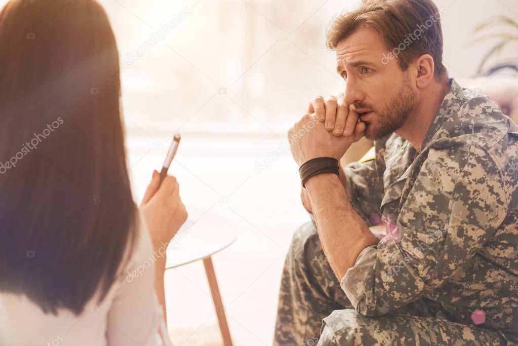 Sad military man wrinkling his forehead