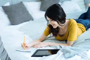 Yatakta notlar alarak neşeli genç esmer