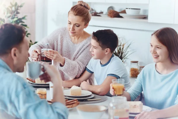 Omtänksamma mor att ta hand om familjen under frukosten — Stockfoto