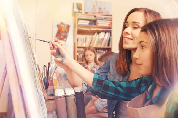 Artista femenina ayudando a una joven estudiante con pintura abstracta — Foto de Stock