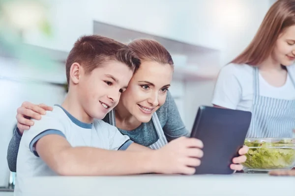 Мальчик с каштановыми волосами показывает маме цифровой планшет — стоковое фото