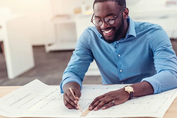 Lachende mannelijke ingenieur bezig met technische tekening aan tafel — Stockfoto