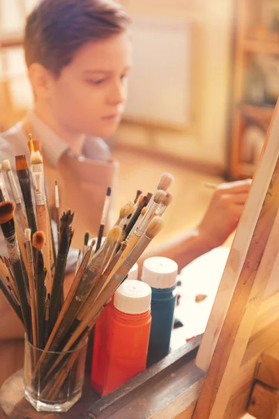 Jovem artista focado pintura sobre tela de arte em estúdio — Fotografia de Stock