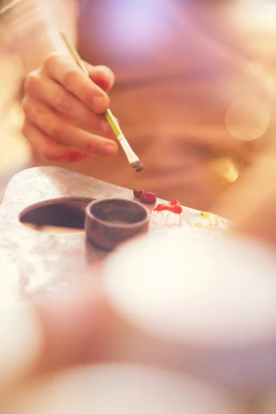 Close up of child hand mixing oil paints on palette — Stock Photo, Image